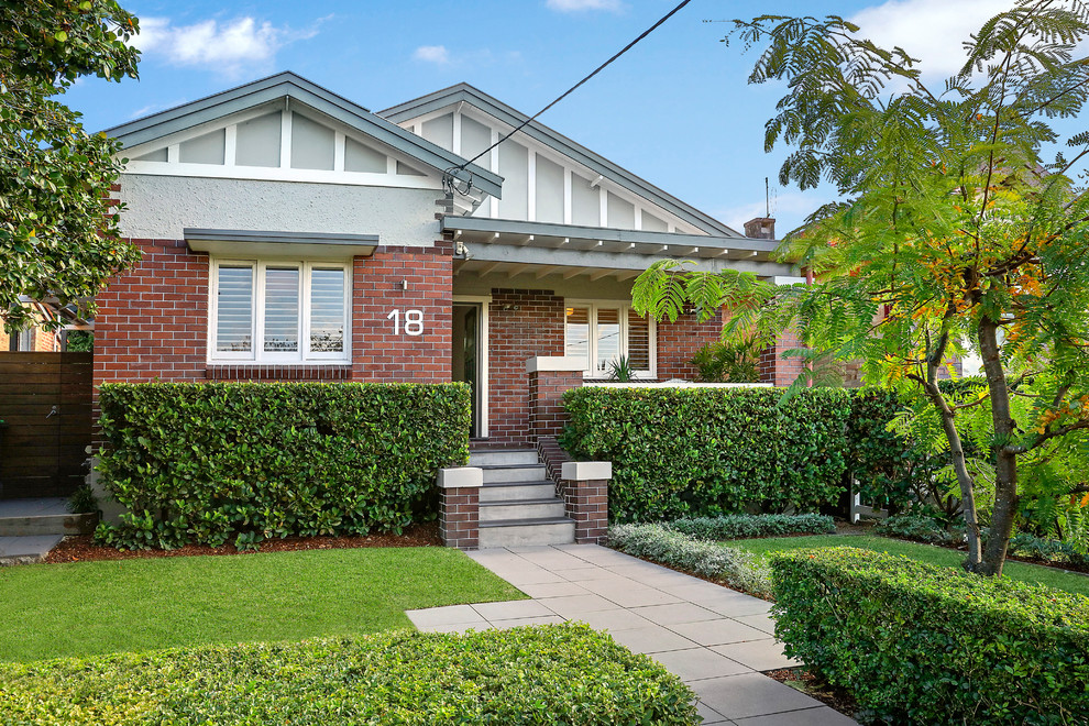 Photo of a mid-sized transitional one-storey brick brown house exterior in Sydney with a gable roof and a tile roof.