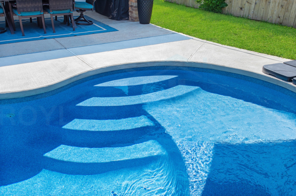 Example of a mid-sized backyard custom-shaped pool design with decking