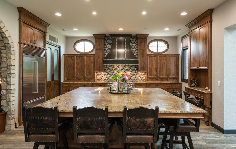 This is an example of a large traditional u-shaped eat-in kitchen in Detroit with recessed-panel cabinets, dark wood cabinets, granite benchtops, multi-coloured splashback, mosaic tile splashback, stainless steel appliances, dark hardwood floors, with island, grey floor and beige benchtop.