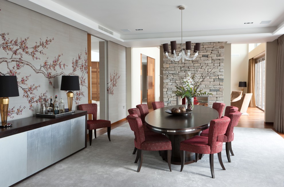 This is an example of a contemporary dining room in London with a two-sided fireplace, a stone fireplace surround and beige walls.