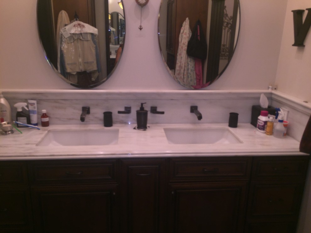 Photo of a traditional bathroom in Los Angeles with dark wood cabinets and marble benchtops.