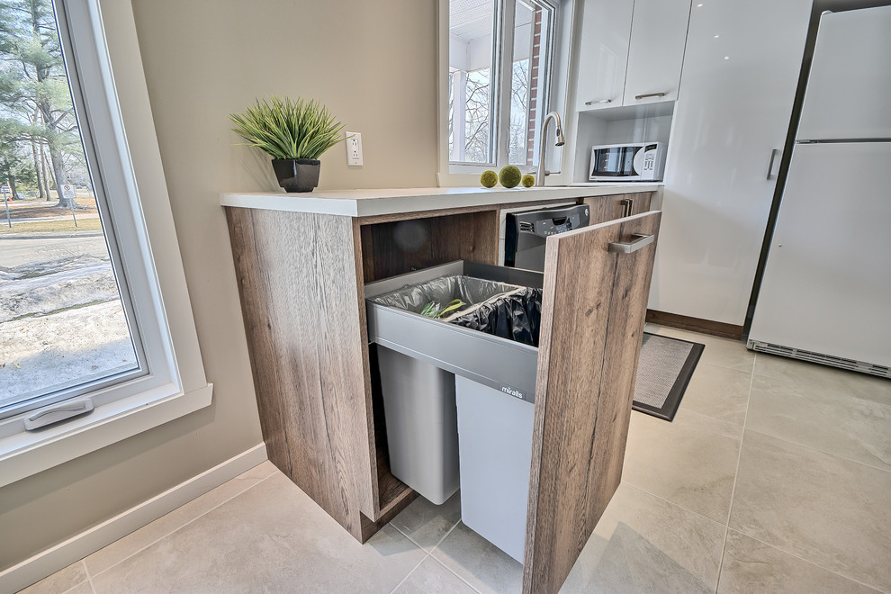 Small contemporary l-shaped eat-in kitchen in Montreal with an undermount sink, flat-panel cabinets, light wood cabinets, laminate benchtops, white splashback, subway tile splashback, white appliances, ceramic floors and a peninsula.