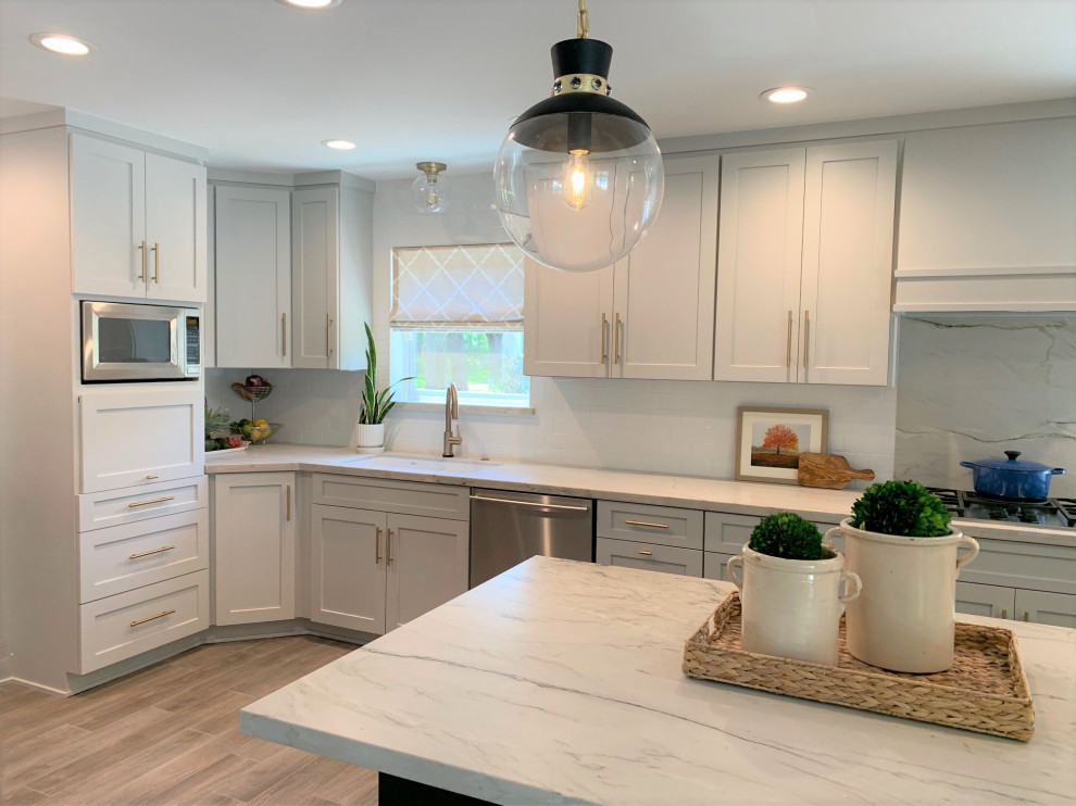 Modern inredning av ett stort vit vitt u-kök, med en undermonterad diskho, skåp i shakerstil, grå skåp, bänkskiva i kvartsit, vitt stänkskydd, stänkskydd i keramik, rostfria vitvaror, klinkergolv i porslin, en köksö och grått golv