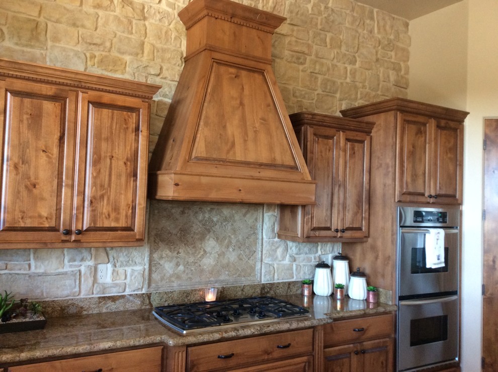 Mountain style kitchen photo in Phoenix with raised-panel cabinets, medium tone wood cabinets, granite countertops, beige backsplash, stone tile backsplash and stainless steel appliances