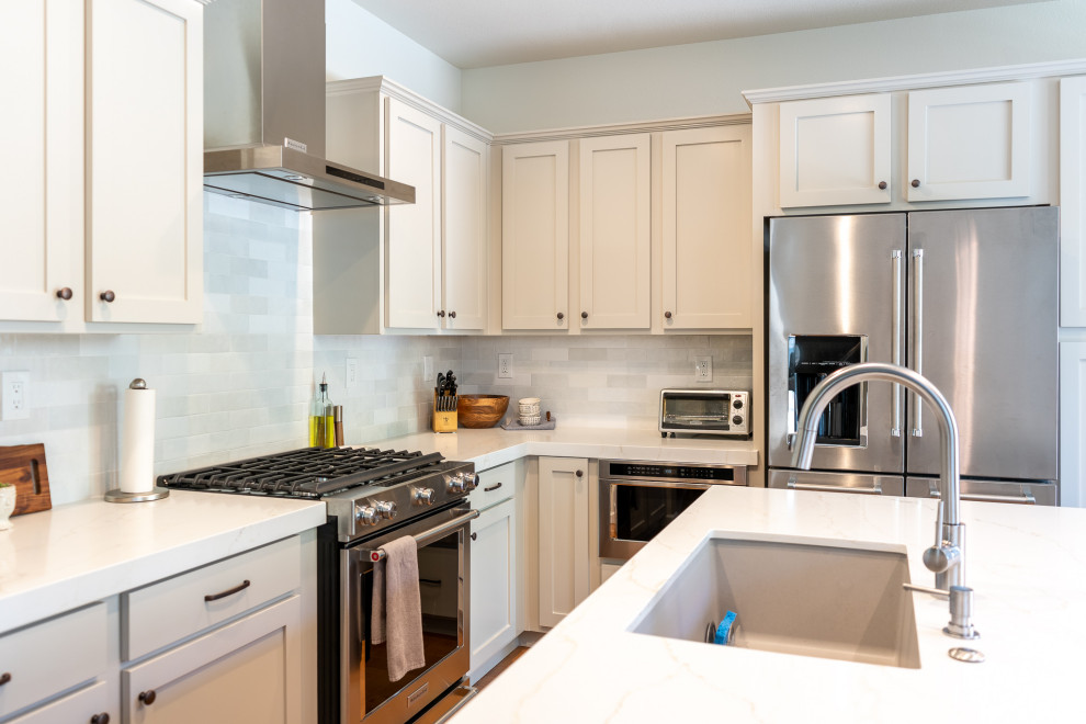 This is an example of a modern l-shaped eat-in kitchen in Sacramento with an undermount sink, beige cabinets, quartz benchtops, white splashback, ceramic splashback, stainless steel appliances, with island and white benchtop.