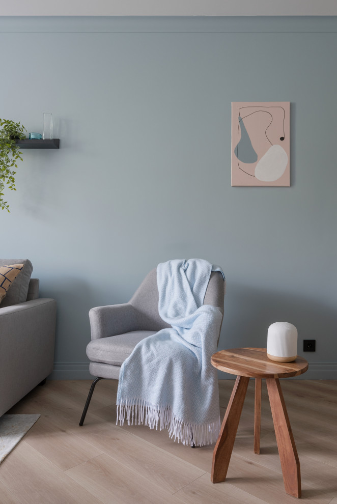 На фото: серо-белая гостиная комната среднего размера в современном стиле с серыми стенами, полом из ламината, телевизором на стене, бежевым полом и панелями на части стены с