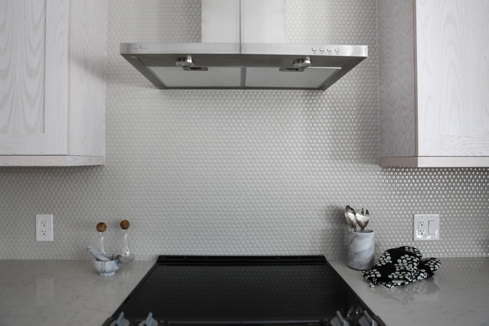 Example of a mid-sized transitional galley light wood floor eat-in kitchen design with an undermount sink, shaker cabinets, white cabinets, gray backsplash, stainless steel appliances, an island, marble countertops and stone tile backsplash