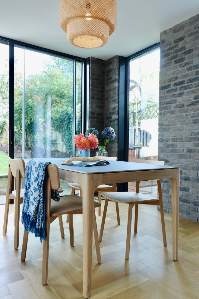 Immagine di una sala da pranzo aperta verso il soggiorno stile americano di medie dimensioni con pareti marroni, pavimento in legno verniciato e pareti in mattoni