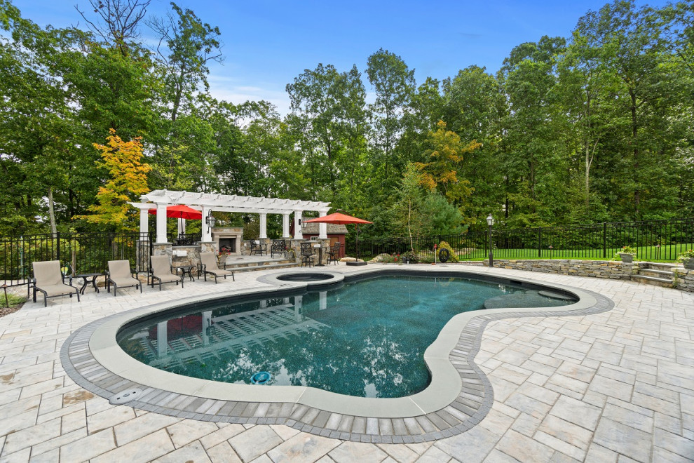 Пример оригинального дизайна: большой бассейн произвольной формы на заднем дворе в классическом стиле с мощением тротуарной плиткой