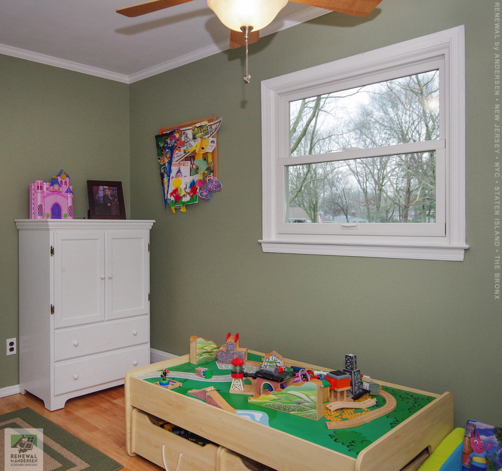 Bild på ett mellanstort barnrum kombinerat med sovrum, med gröna väggar, ljust trägolv och flerfärgat golv
