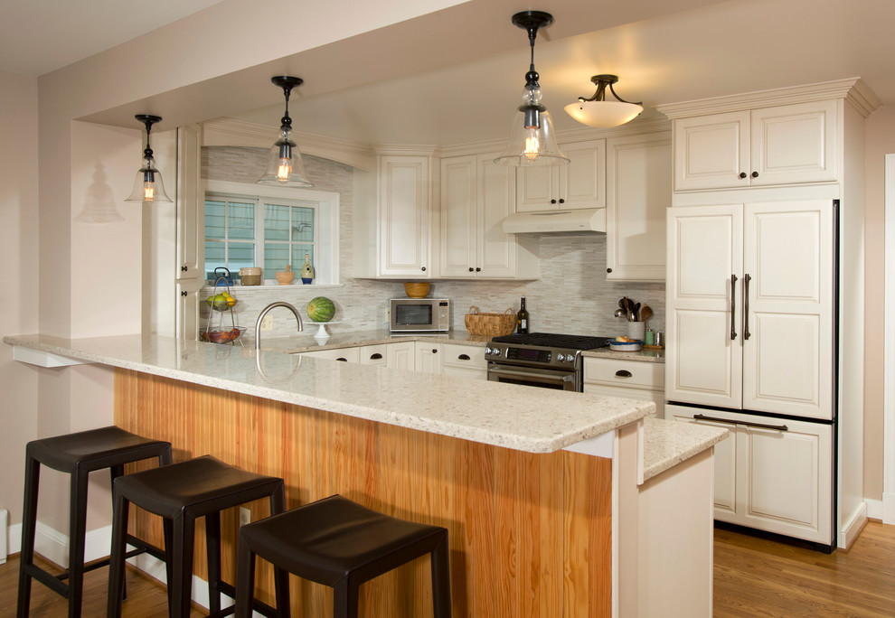 Photo of a traditional u-shaped kitchen in DC Metro with an undermount sink, recessed-panel cabinets, white cabinets, beige splashback, matchstick tile splashback, stainless steel appliances and medium hardwood floors.