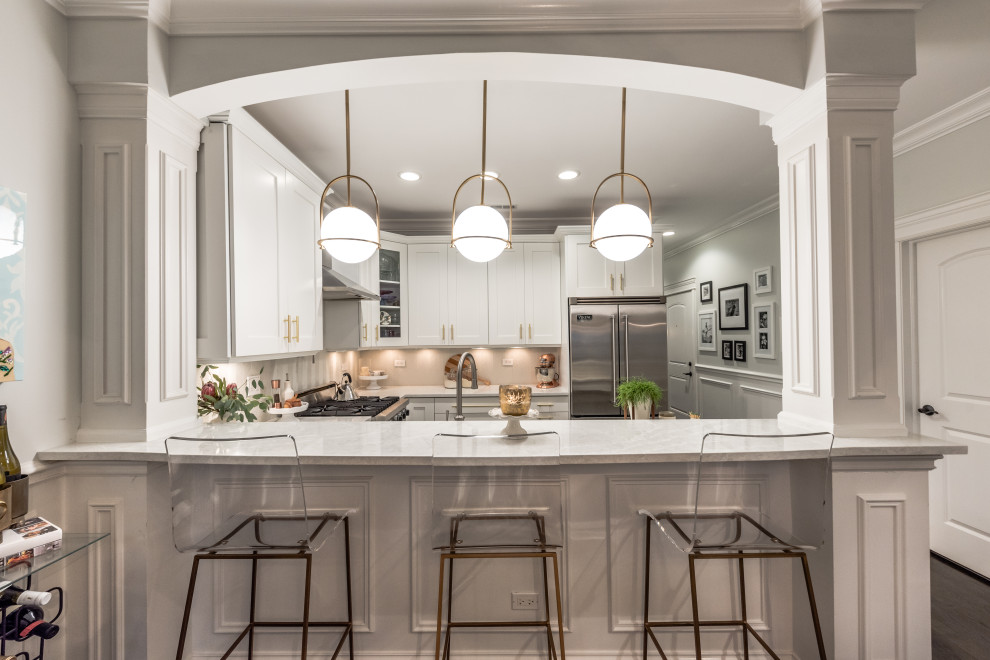 Inspiration for a mid-sized transitional u-shaped dark wood floor and brown floor eat-in kitchen remodel in Chicago with a farmhouse sink, shaker cabinets, white cabinets, quartz countertops, gray backsplash, glass tile backsplash, stainless steel appliances, a peninsula and gray countertops