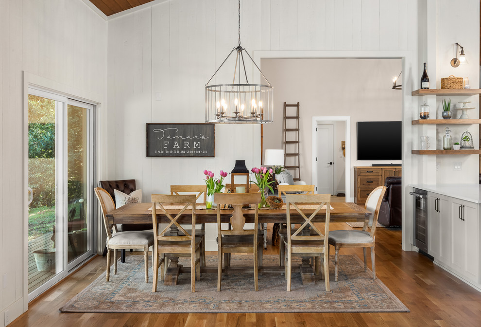 Country dining room in Portland with white walls, medium hardwood floors and brown floor.