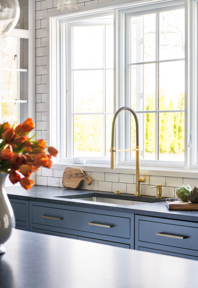 Kitchen - mid-sized transitional u-shaped medium tone wood floor and brown floor kitchen idea in New York with a single-bowl sink, shaker cabinets, blue cabinets, granite countertops, white backsplash, ceramic backsplash, paneled appliances, an island and black countertops