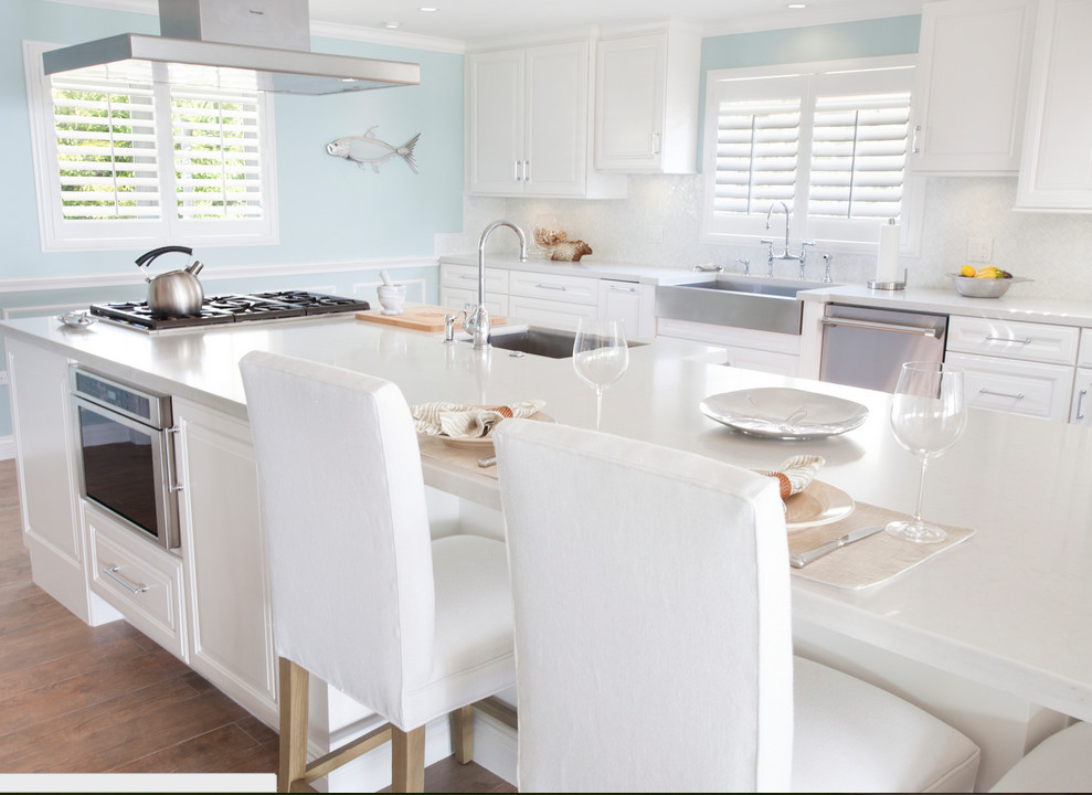 Open concept kitchen - large transitional galley porcelain tile and brown floor open concept kitchen idea in Miami with a farmhouse sink, raised-panel cabinets, white cabinets, quartz countertops, white backsplash, porcelain backsplash, stainless steel appliances and an island