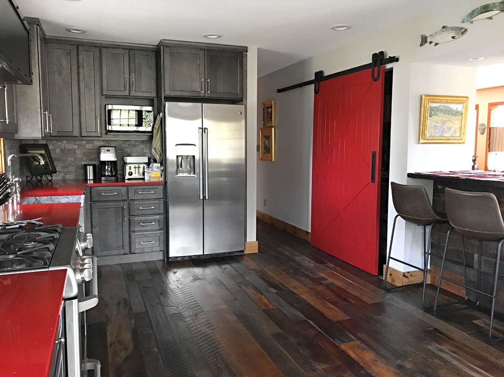 This is an example of a mid-sized transitional l-shaped eat-in kitchen in Denver with a farmhouse sink, shaker cabinets, grey cabinets, quartz benchtops, grey splashback, stainless steel appliances, dark hardwood floors, no island and red benchtop.