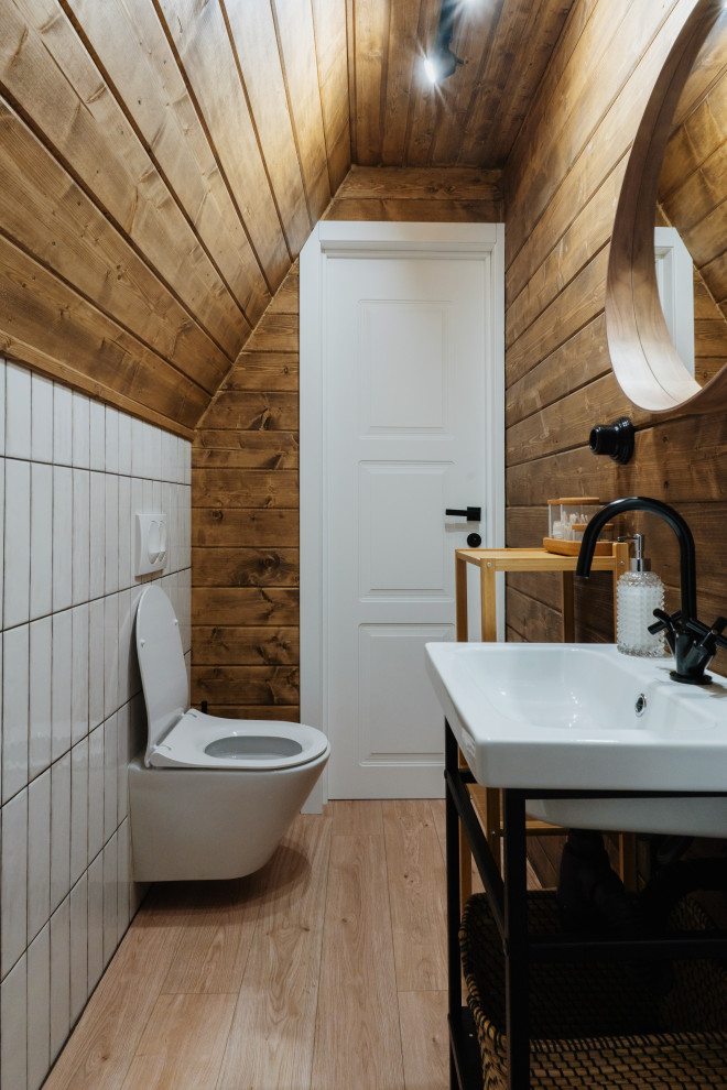 Пример оригинального дизайна: туалет в скандинавском стиле с инсталляцией, белой плиткой, керамической плиткой, белыми стенами, полом из винила, деревянным потолком и деревянными стенами