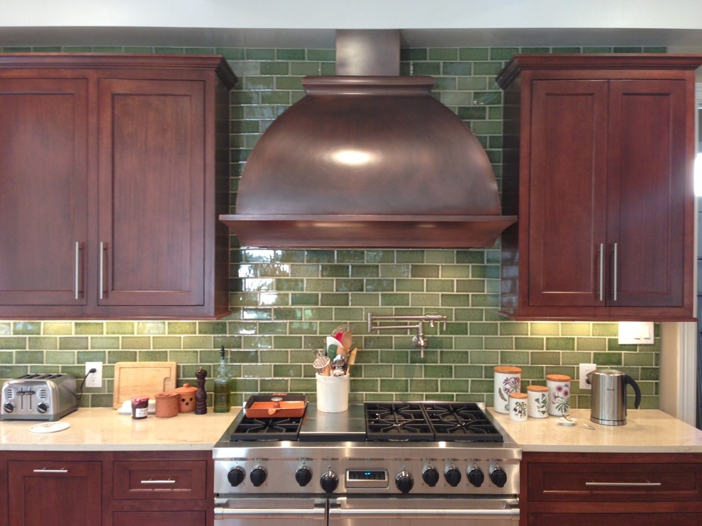 Photo of a mid-sized traditional kitchen in Austin with shaker cabinets, dark wood cabinets, solid surface benchtops, green splashback, glass tile splashback and stainless steel appliances.