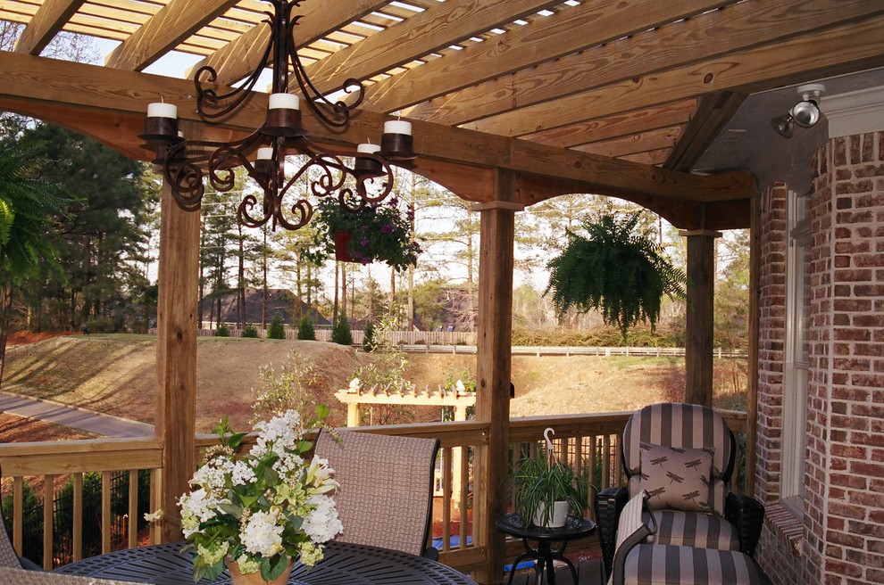 This is an example of a large mediterranean backyard deck in Atlanta with a pergola.