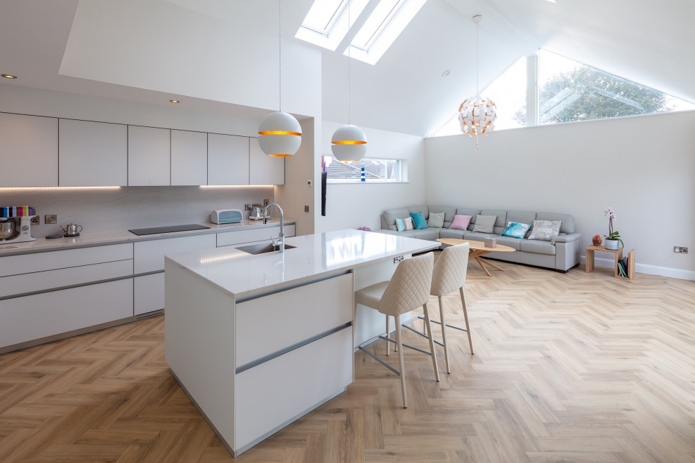 Design ideas for a mid-sized contemporary l-shaped open plan kitchen in Other with a drop-in sink, flat-panel cabinets, white cabinets, marble benchtops, white splashback, marble splashback, panelled appliances, light hardwood floors, with island, brown floor and white benchtop.