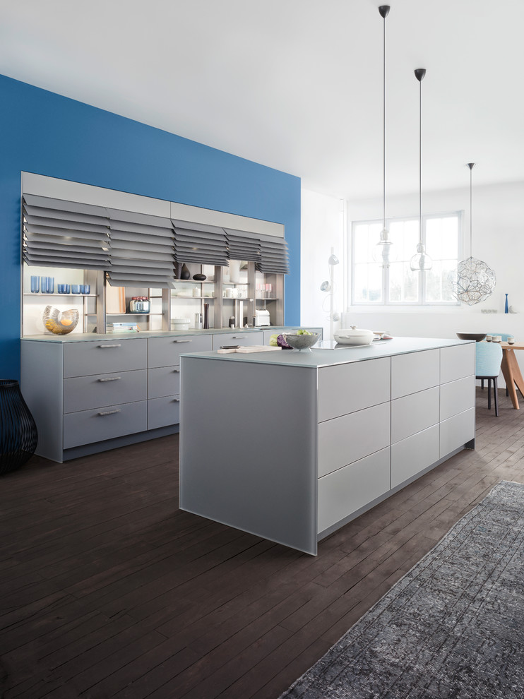 Large u-shaped dark wood floor eat-in kitchen photo in Orange County with an undermount sink, glass-front cabinets, gray cabinets, glass countertops, gray backsplash, stainless steel appliances and an island