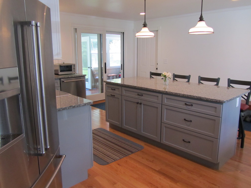 Photo of a mid-sized country l-shaped eat-in kitchen in Providence with a single-bowl sink, shaker cabinets, grey cabinets, granite benchtops, white splashback, stainless steel appliances, light hardwood floors and with island.