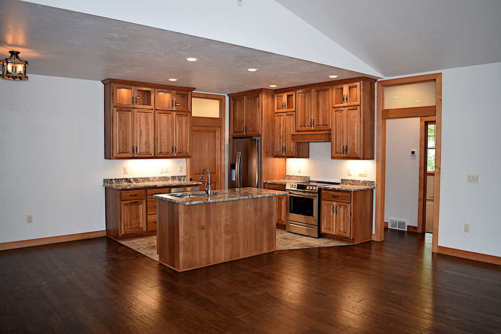 Example of a mid-sized l-shaped open concept kitchen design with an undermount sink, raised-panel cabinets, granite countertops, white backsplash, ceramic backsplash, stainless steel appliances and an island