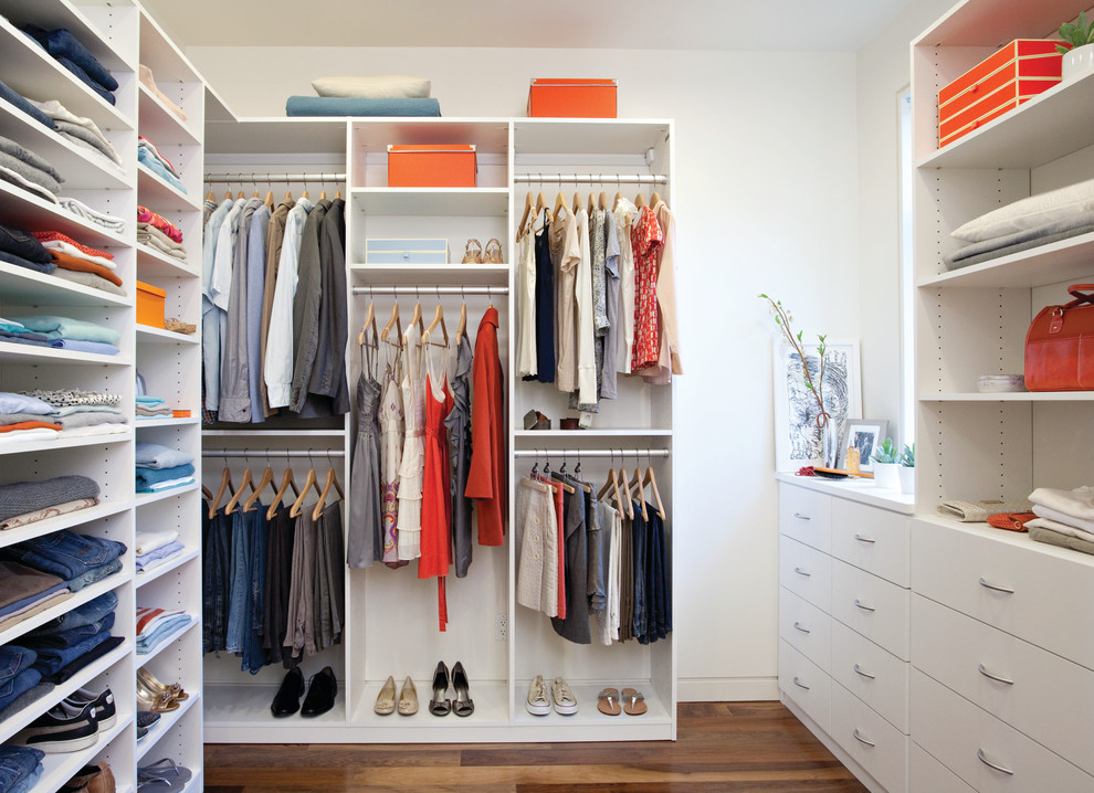Example of a mid-sized trendy gender-neutral medium tone wood floor walk-in closet design in Nashville with white cabinets