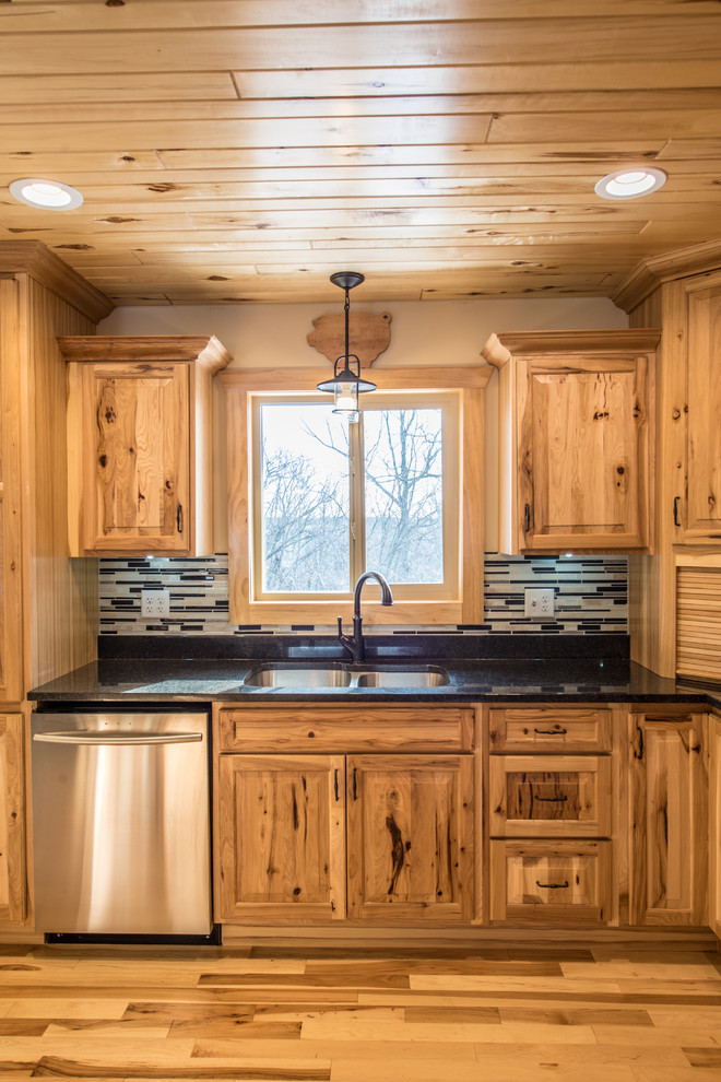 Example of a mid-sized mountain style l-shaped light wood floor open concept kitchen design in Minneapolis with a double-bowl sink, raised-panel cabinets, light wood cabinets, granite countertops, multicolored backsplash, matchstick tile backsplash, stainless steel appliances and an island