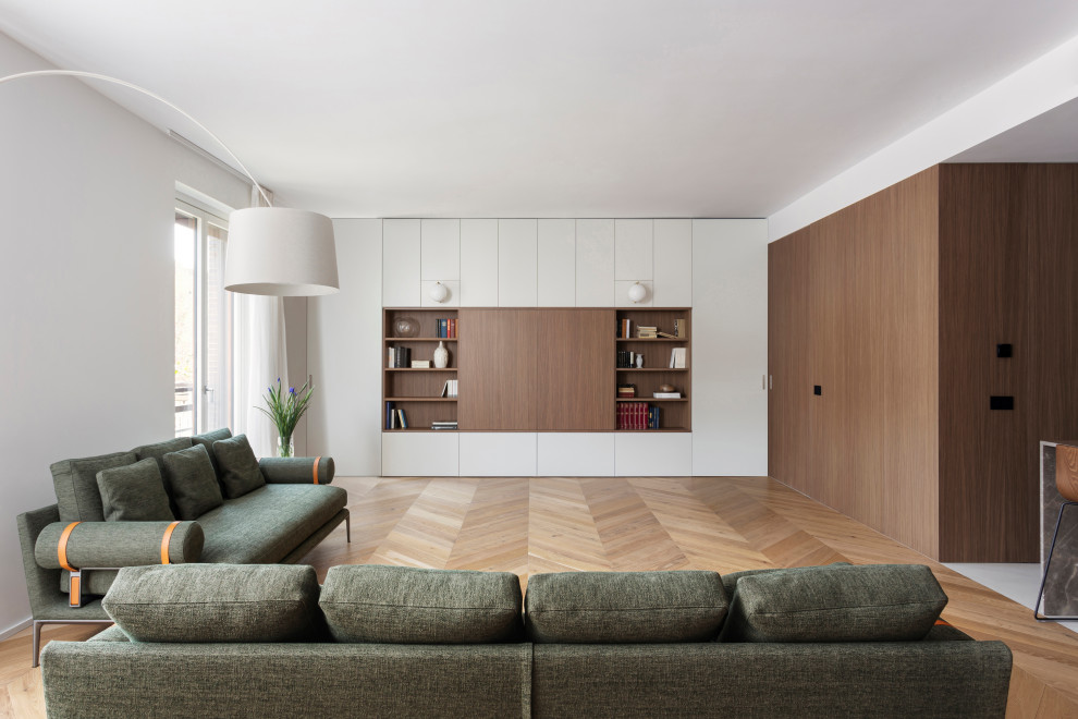 Immagine di un grande soggiorno moderno aperto con pareti bianche, pavimento in legno massello medio e pannellatura