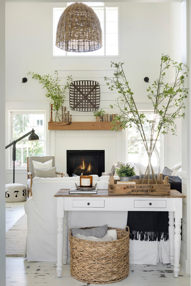 Inspiration for a mid-sized country open concept living room in Minneapolis with white walls, painted wood floors, a wood fireplace surround and white floor.
