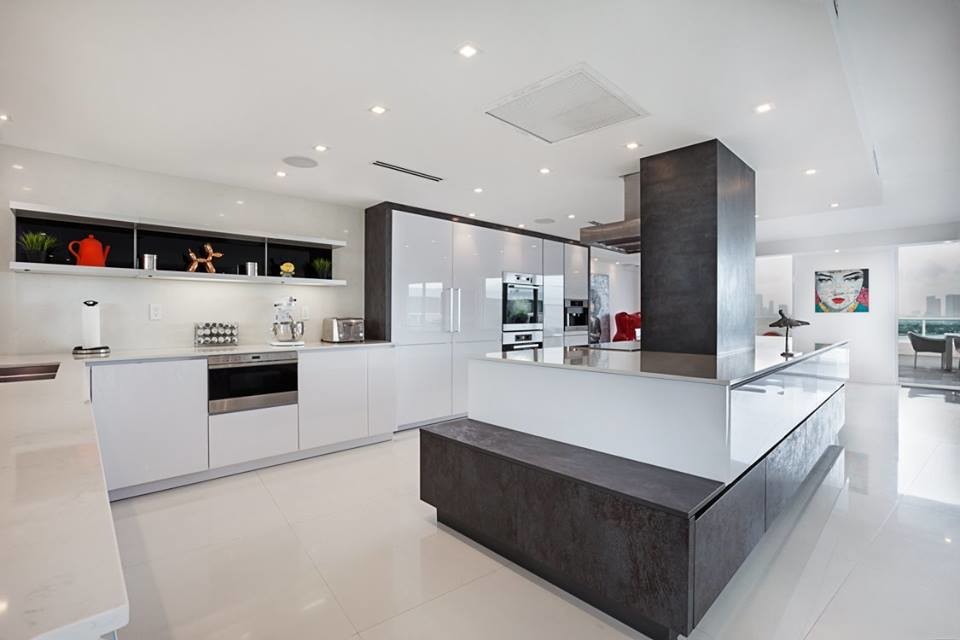 This is an example of a mid-sized modern l-shaped eat-in kitchen in New York with flat-panel cabinets, white cabinets, quartz benchtops, stainless steel appliances, porcelain floors, with island and a double-bowl sink.
