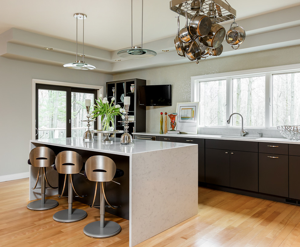 Kitchen - large transitional l-shaped light wood floor kitchen idea with flat-panel cabinets, dark wood cabinets, gray backsplash, stainless steel appliances and an island