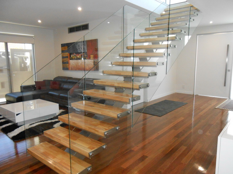 This is an example of a mid-sized modern wood straight staircase in Other with open risers and glass railing.