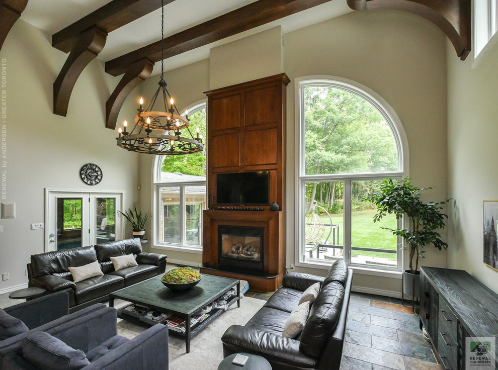 This is an example of a large formal enclosed living room in Toronto with beige walls, terra-cotta floors, a standard fireplace, a wood fireplace surround, a wall-mounted tv, multi-coloured floor and exposed beam.