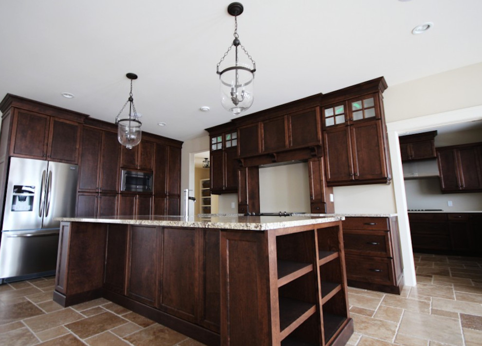 Photo of a mid-sized traditional u-shaped eat-in kitchen in Other with a drop-in sink, flat-panel cabinets, dark wood cabinets, granite benchtops, stainless steel appliances, limestone floors and with island.