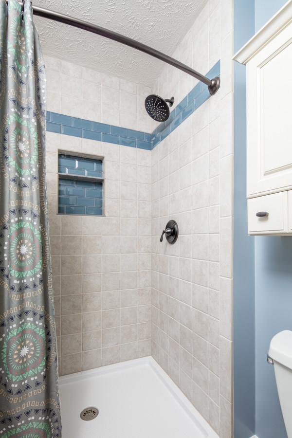 Photo of a small traditional 3/4 bathroom in Omaha with shaker cabinets, beige cabinets, an alcove shower, a two-piece toilet, beige tile, ceramic tile, blue walls, ceramic floors, an integrated sink, multi-coloured floor and a shower curtain.