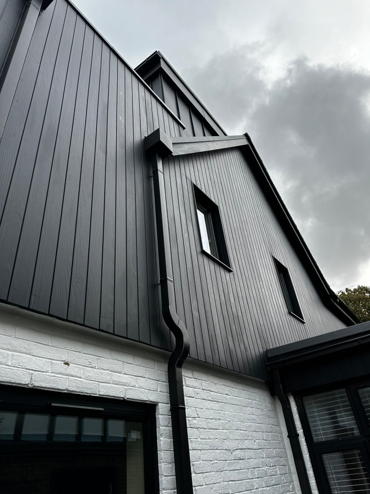 Diseño de fachada de casa negra y negra contemporánea grande de tres plantas con revestimientos combinados, tejado plano y tejado de metal