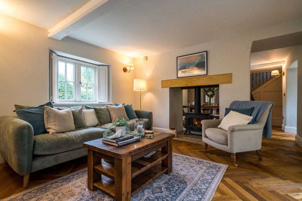 This is an example of a medium sized farmhouse formal enclosed living room in Gloucestershire with grey walls, dark hardwood flooring, a two-sided fireplace, a plastered fireplace surround, a wall mounted tv, brown floors and panelled walls.