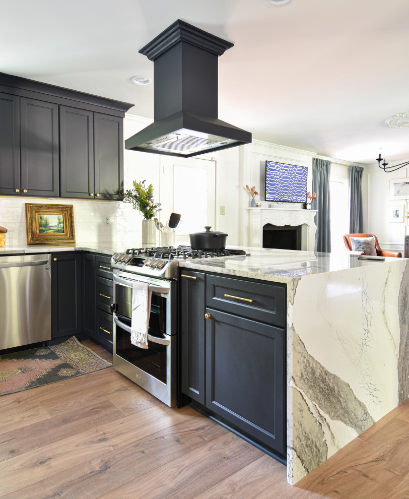 Photo of a mid-sized transitional u-shaped open plan kitchen in Other with a farmhouse sink, black cabinets, quartzite benchtops, white splashback, laminate floors and a peninsula.