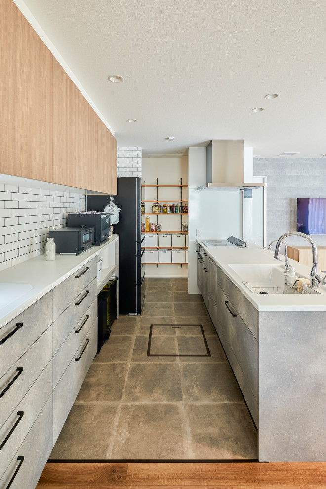 Mid-sized single-wall open plan kitchen in Nagoya with beaded inset cabinets, grey cabinets, white splashback, black appliances, cement tiles, with island, grey floor, white benchtop and wallpaper.