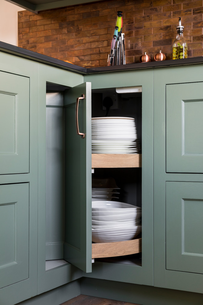 Mid-sized traditional u-shaped eat-in kitchen in Kent with a farmhouse sink, shaker cabinets, green cabinets, quartz benchtops, metal splashback, linoleum floors, a peninsula and green floor.