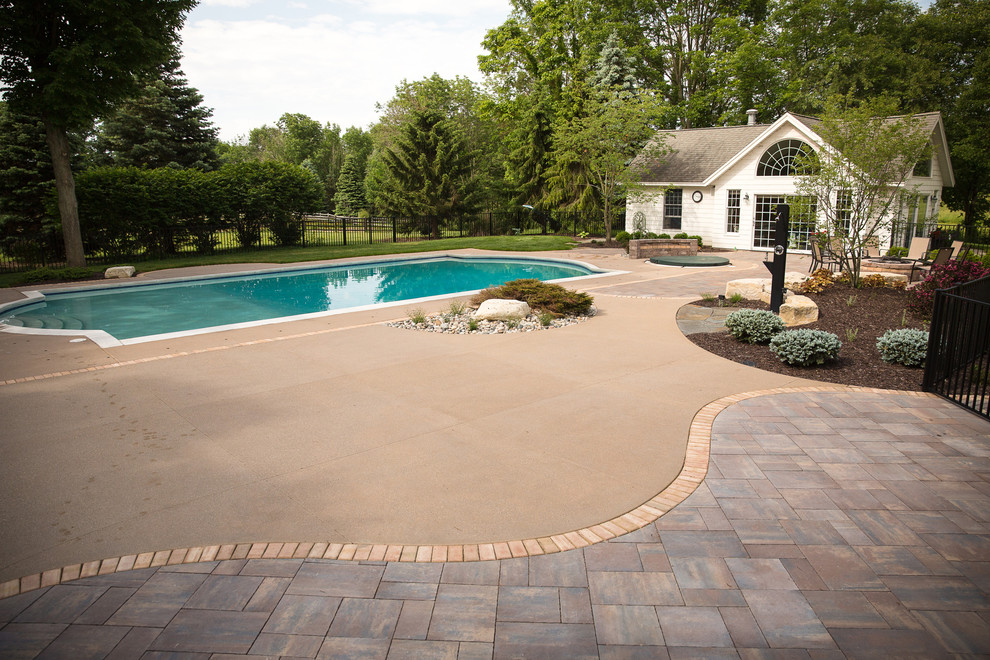 Inspiration for a large country backyard custom-shaped pool in Grand Rapids with a pool house and concrete slab.