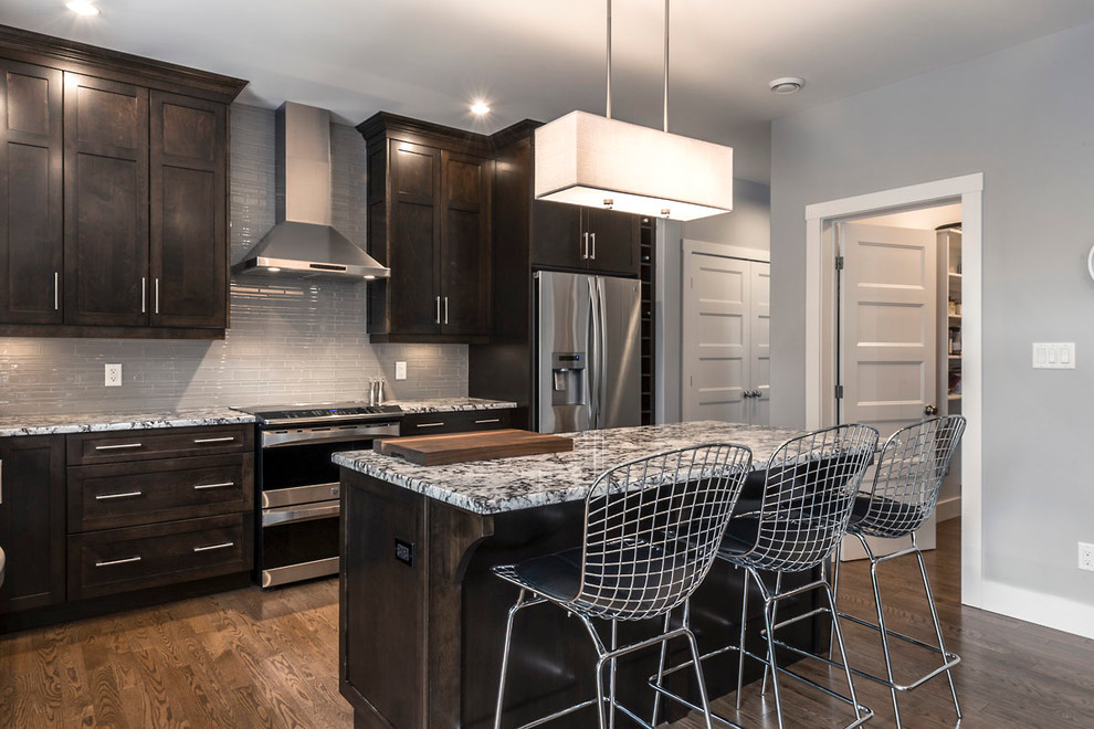 Eat-in kitchen - mid-sized transitional l-shaped dark wood floor eat-in kitchen idea with an undermount sink, shaker cabinets, dark wood cabinets, granite countertops, gray backsplash, glass tile backsplash, stainless steel appliances and an island