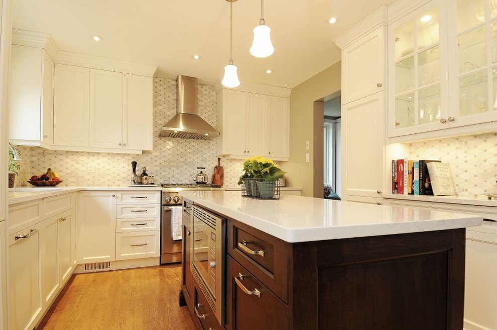 Kitchen - mid-sized transitional l-shaped medium tone wood floor kitchen idea in Ottawa with a double-bowl sink, recessed-panel cabinets, white cabinets, quartz countertops, gray backsplash, stone tile backsplash, stainless steel appliances and an island