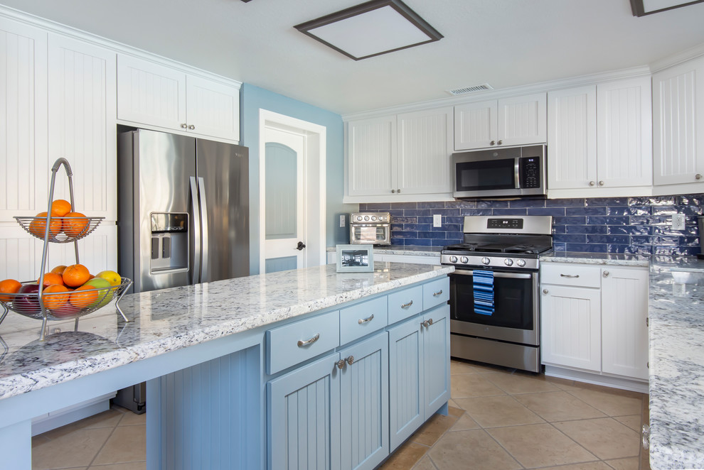Photo of a mid-sized transitional galley separate kitchen in Los Angeles with a single-bowl sink, beaded inset cabinets, white cabinets, granite benchtops, blue splashback, ceramic splashback, stainless steel appliances, ceramic floors, with island, beige floor and blue benchtop.