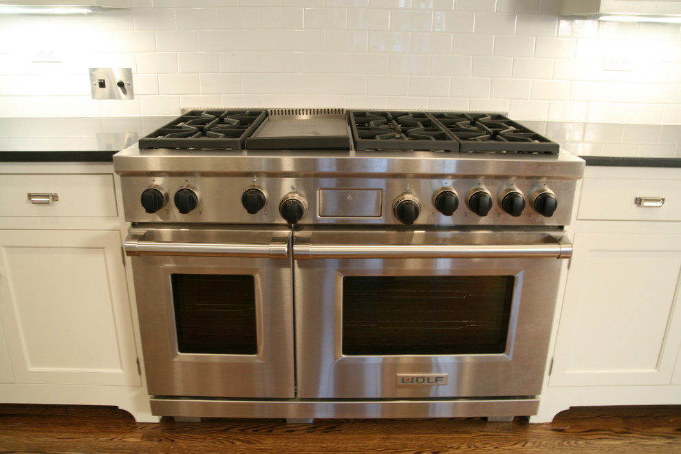 Open concept kitchen - large transitional l-shaped dark wood floor open concept kitchen idea in Chicago with white cabinets, white backsplash, subway tile backsplash, stainless steel appliances and an island