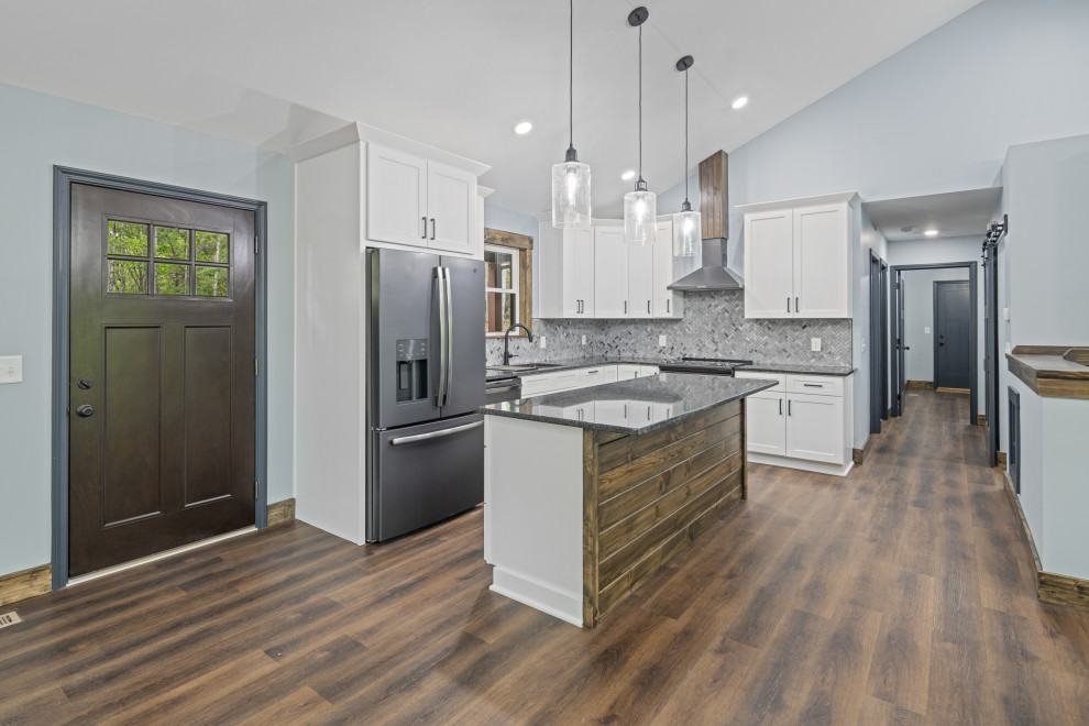 Inspiration for a rustic l-shaped vinyl floor, brown floor and vaulted ceiling eat-in kitchen remodel in Charlotte with shaker cabinets, white cabinets, granite countertops, gray backsplash, mosaic tile backsplash, stainless steel appliances, an island and gray countertops