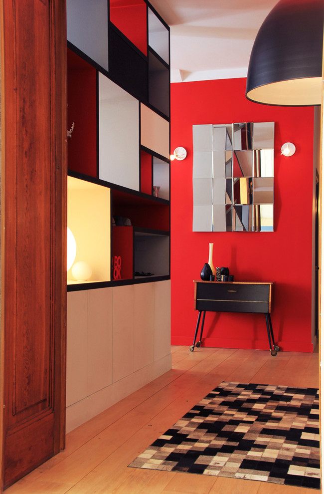 Photo of a mid-sized contemporary foyer in Paris with red walls and light hardwood floors.