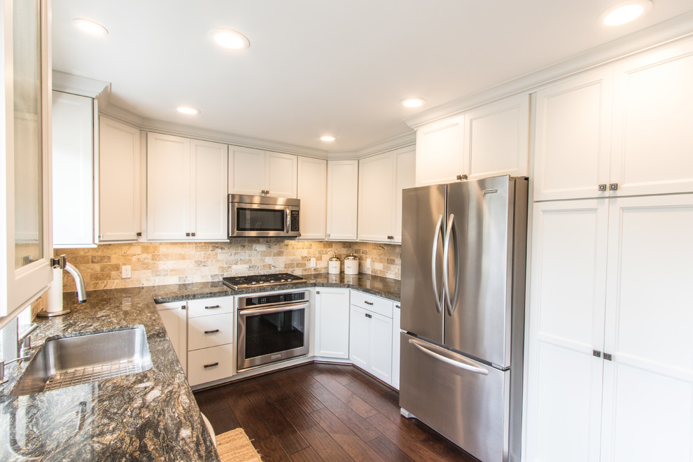 This is an example of a mid-sized arts and crafts u-shaped eat-in kitchen in Orange County with a single-bowl sink, recessed-panel cabinets, white cabinets, granite benchtops, brown splashback, stone tile splashback, stainless steel appliances, with island and medium hardwood floors.
